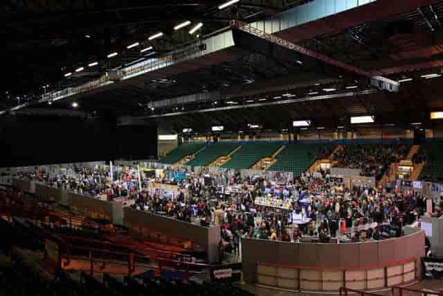 Trade show floor in Utilita Arena auditorium with tiered seating for corporate event exhibition.