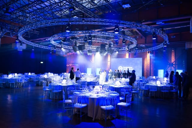 Gala banquet at Grand Milan Mecenate with circular truss lighting for industrial event venue.