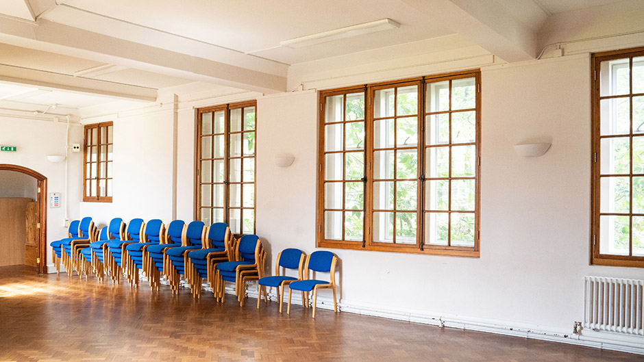 Spacious lecture room with blue chairs, perfect for workshops and gatherings. - Banner