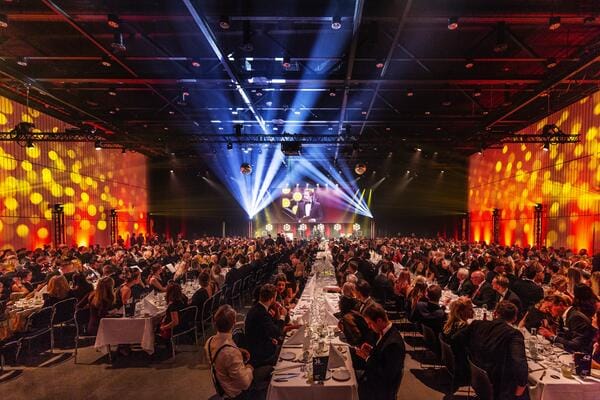 Gala dinner in Venuu convention center with banquet seating and stage production.