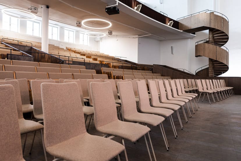 Minimalist tiered auditorium with architectural staircase for business conferences and lectures.