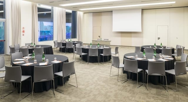 AC Hotel Milano banquet room with round tables for corporate workshops and business events.