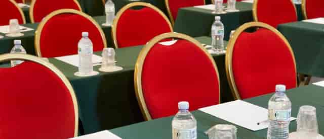 Classroom-style dining room setup with red chairs for corporate workshop or seminar.