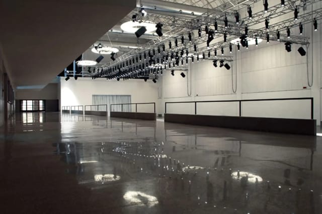 Industrial-chic foyer venue at La Pelota with overhead rigging for production and events.