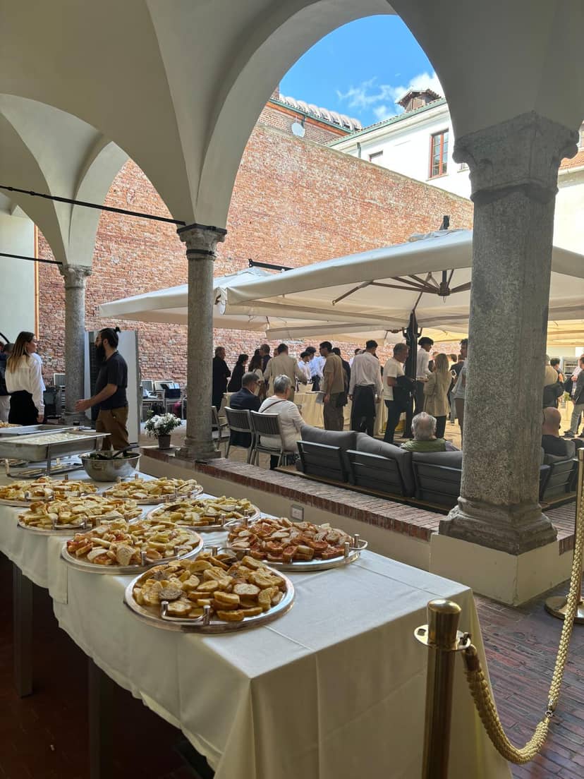 Corporate networking reception at I Chiostri di San Barnaba courtyard with event lounge seating.