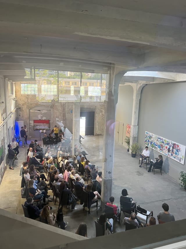 Industrial-chic panel discussion venue at Galleria LAMPO with exposed architecture.