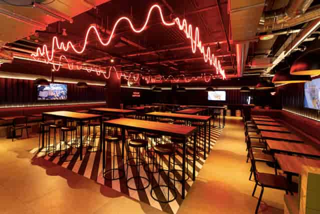 Industrial-chic networking venue with neon lighting, perfect for corporate events and mixers.
