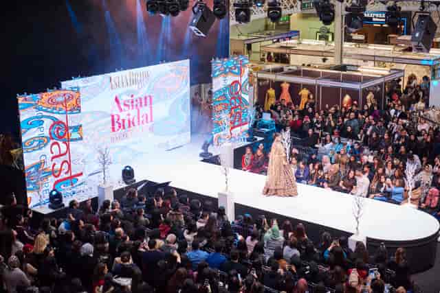 Vibrant fashion show at The National Hall, Olympia with elegant stage design.