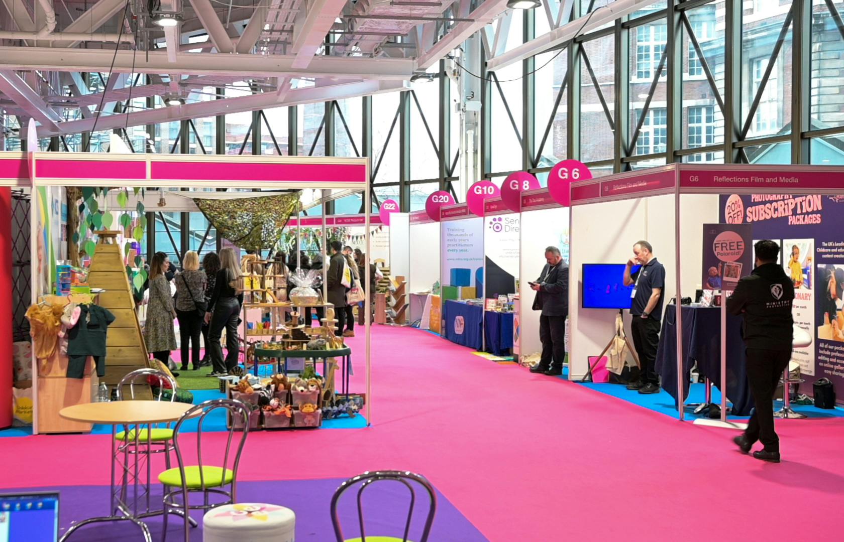 Vibrant exhibition space in West Hall, Olympia with colorful booths and networking opportunities.