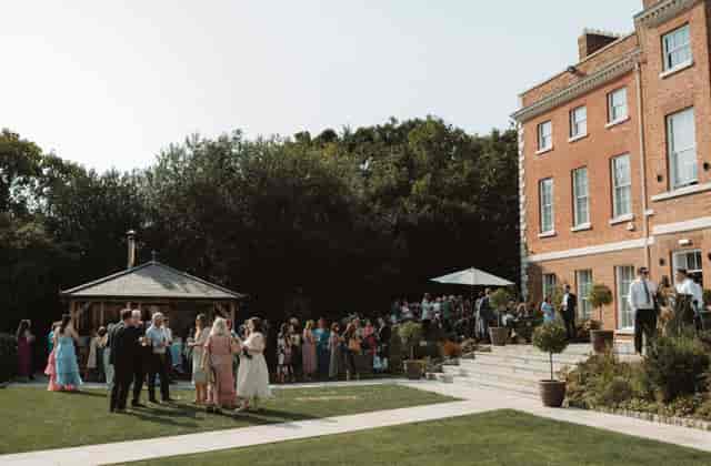 Outdoor summer party at Old Palace Chester with lush greenery and elegant architecture.