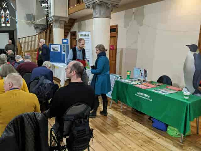 Community engagement event at Elmgrove Centre with exhibition booths and seated audience.