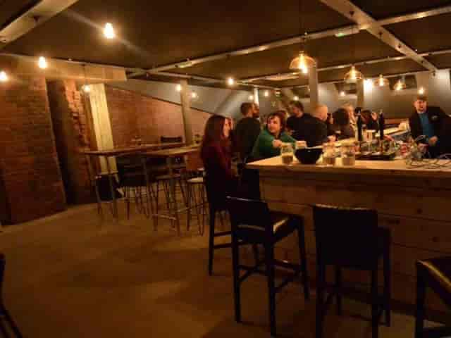 Industrial-chic pub interior with high-top seating for corporate networking and business mixers.