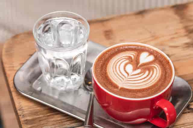 Latte with water at Breakfast Green Quarter Manchester for premium breakfast meetings.