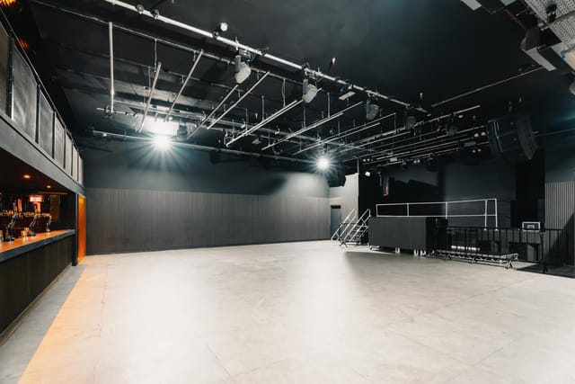 Industrial black box venue with overhead lighting for corporate events and brand activations.