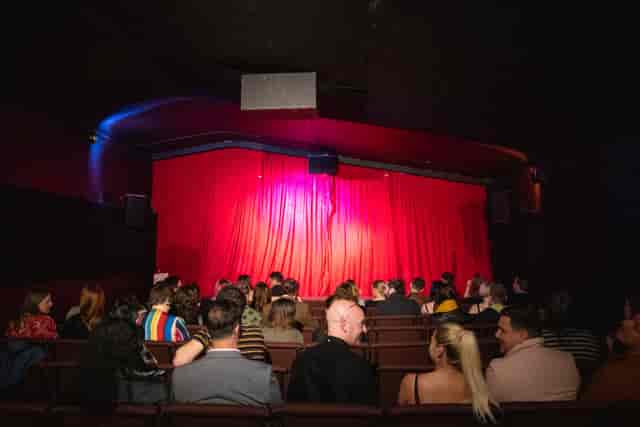 Cultplex screening room with red curtains for comedy shows and intimate theatrical performances.