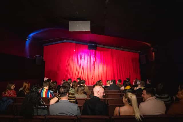 Cultplex screening room with red curtains for comedy shows and intimate theatrical performances.