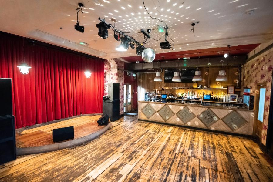Versatile event space at The Deaf Institute with stage, bar, and ambient lighting. - Banner