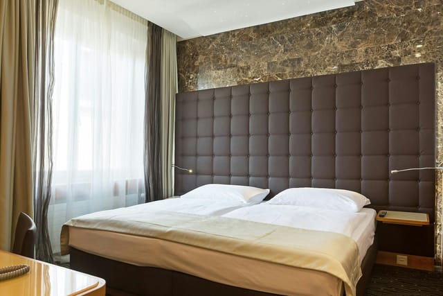 Hotel St. Gotthard guest room with tufted headboard for corporate group travel and business events.