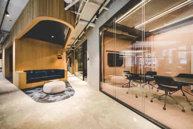 Modern glass boardroom and breakout nook for hybrid corporate meetings and creative workshops.
