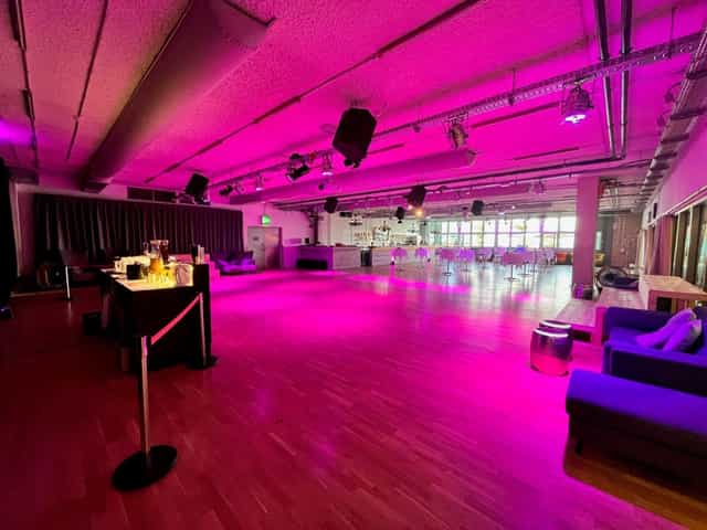 Eventsaal eins0eins industrial reception space with magenta mood lighting for corporate events.