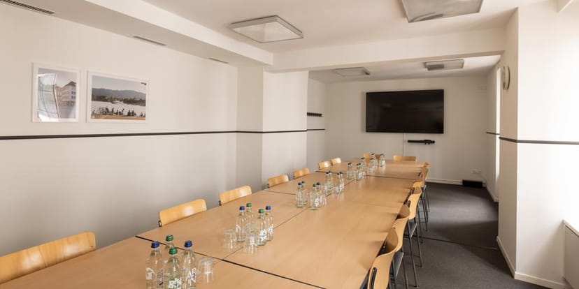 Boardroom meeting room with wood table, display screen, and glassware for corporate events.