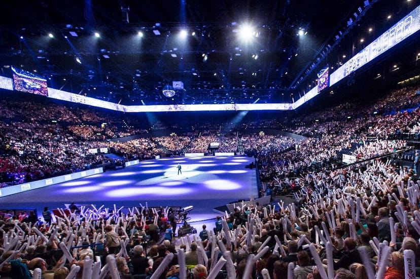 Hallenstadion arena concert with LED branding and glowing audience lights for live event production.
