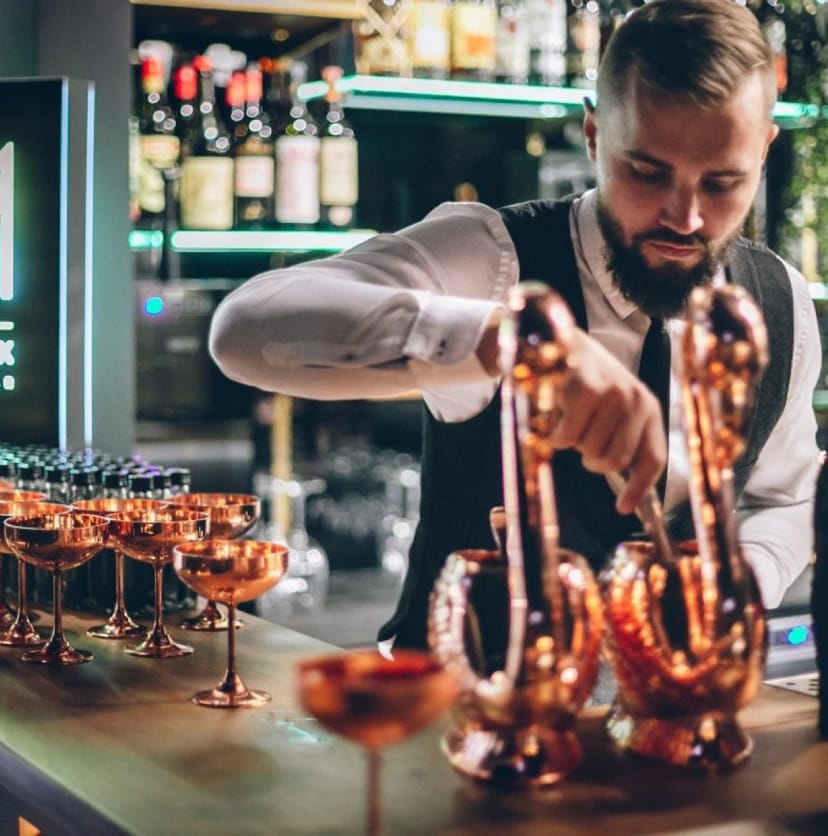 Professional bartender serving at an upscale cocktail bar for corporate events and evening receptions.