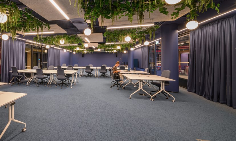 Biophilic coworking meeting space with modular tables for corporate off-sites and workshops.