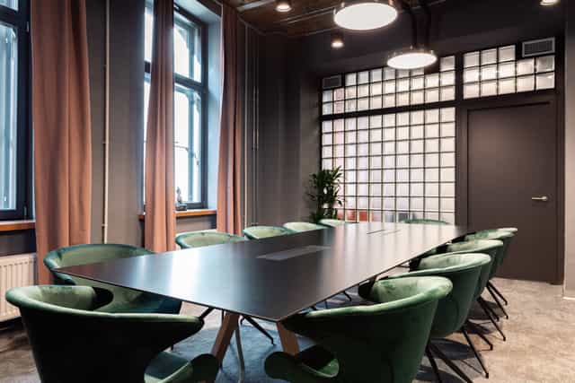 Emerald velvet boardroom with industrial accents for executive strategy and small-group meetings.