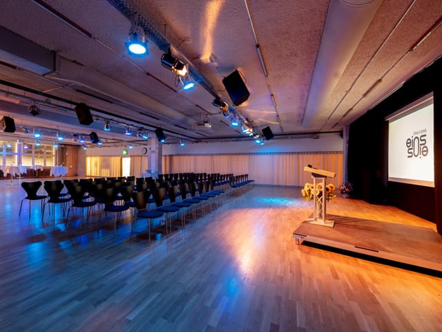 Saal 3 industrial plenary space with stage, ideal for corporate presentations and product launches.