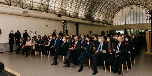 Engaged audience at MEEU Chamartin conference with masks and professional lighting.