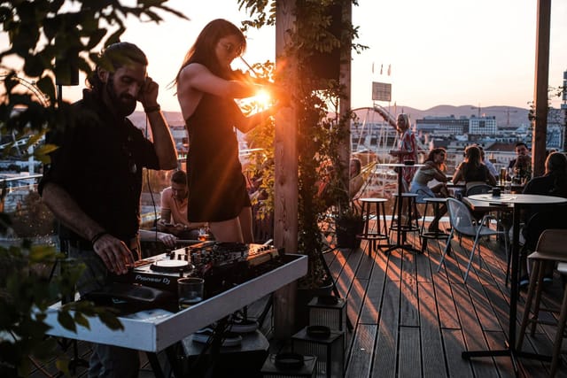 Sunset rooftop reception at Zoku Vienna with live DJ and violinist entertainment.
