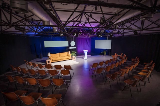 Industrial studio space for fireside chats and panel discussions with lounge seating and screens.