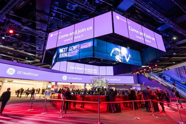 polySTAGE exhibition stand with overhead digital signage at an Austria Center Vienna trade show.