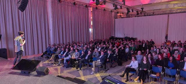 Full capacity theater-style breakout session with professional AV lighting for corporate events.