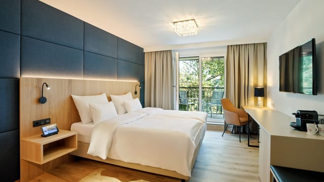 Modern Hotel Maximilian guest room with workspace for corporate event business travel.