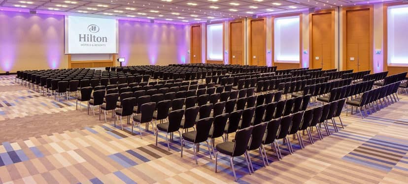 Hilton Vienna Park ballroom, theater-style seating with purple lighting for corporate conferences.