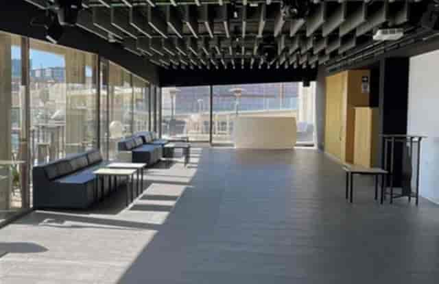 Modern event space with floor-to-ceiling glass for corporate cocktail receptions and networking.