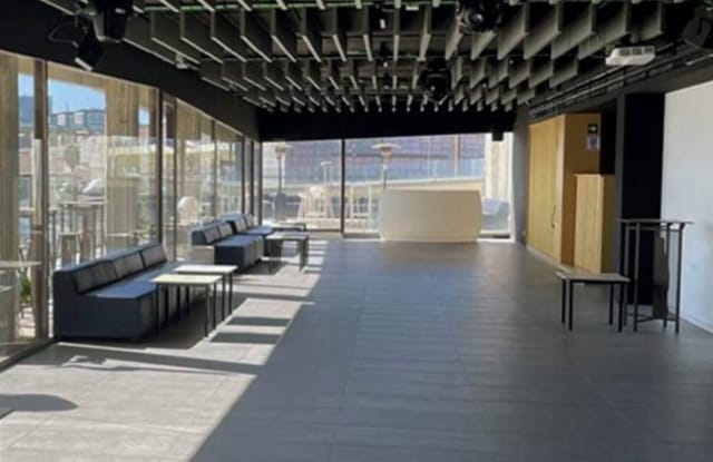 Modern event space with floor-to-ceiling glass for corporate cocktail receptions and networking.