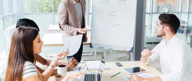 Small group breakout session in Trafford Park office meeting room with flip charts and laptops.