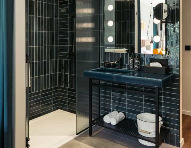 Modern boutique hotel bathroom with dark-tiled decor for premium event room blocks.