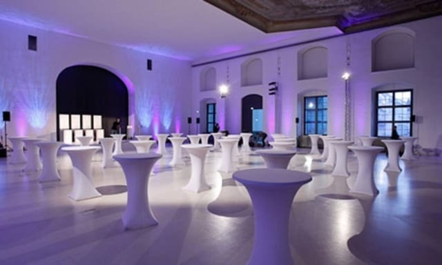 Science Cafe networking reception with modern high-top tables and purple uplighting in event space.