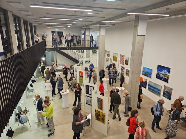 Networking reception in F23 gallery featuring high-top tables for event flow and display walls.