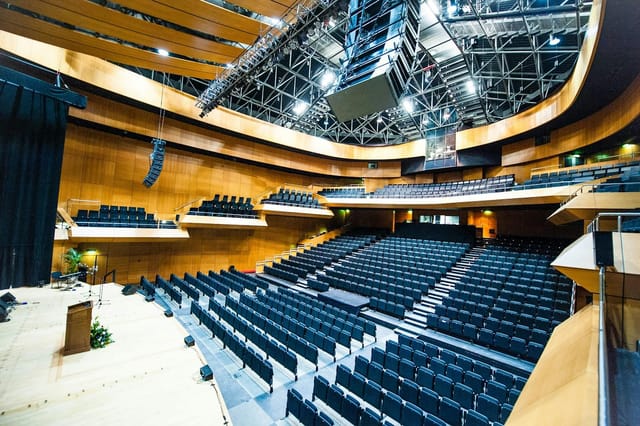 Tiered auditorium at DCU Conferencing Dublin with wood accents for corporate keynotes and events.