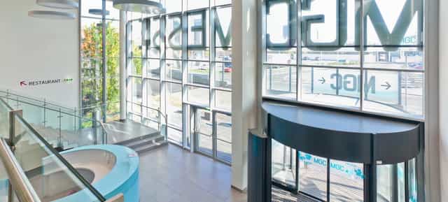 Modern MGC Messe venue foyer with curved reception desk for corporate events and trade shows.