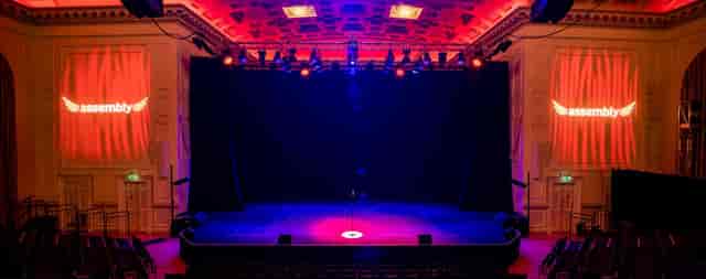 Assembly Hall stage with dramatic downstage lighting for keynote presentation and event venue.