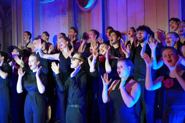 MPAA Academy dance performance in black-tie attire with blue and magenta stage lighting.