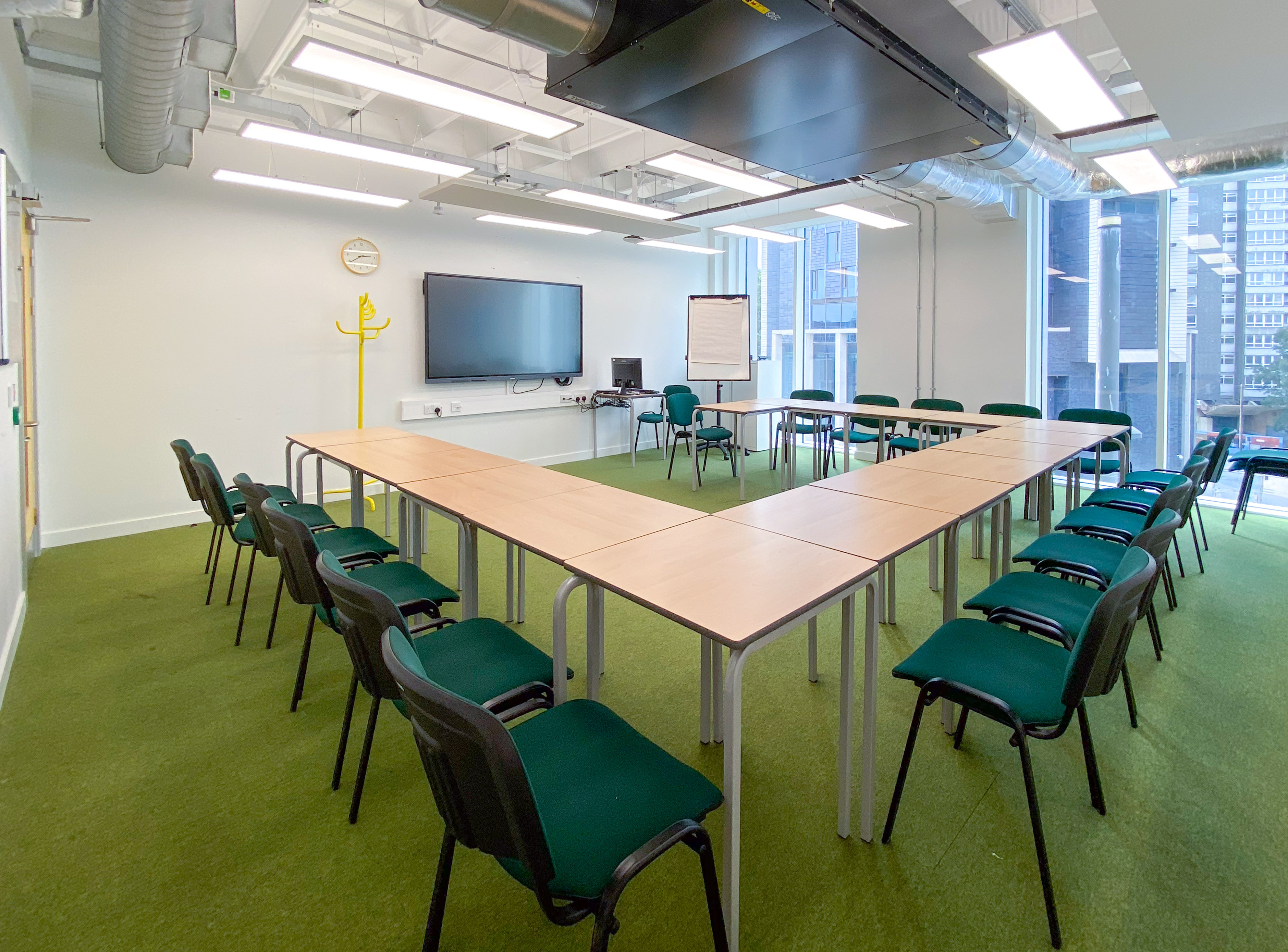 U-shaped meeting room with green carpet, ideal for collaborative discussions and presentations.