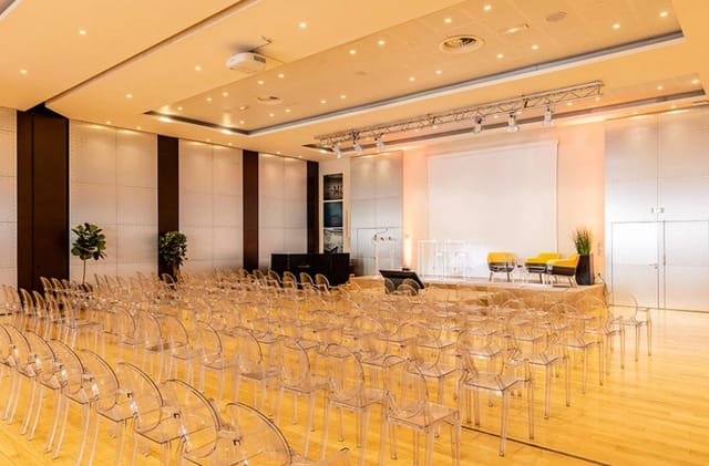 Modern conference room with stage at Salons de l’Aéro-Club for panel discussion or presentation.