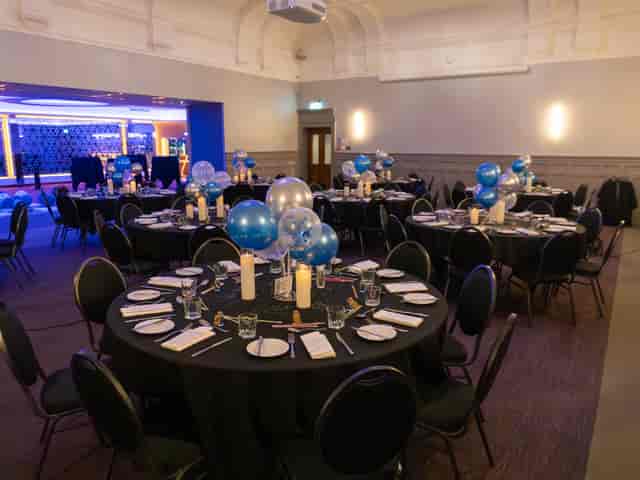 Elegant event space at The Broughton, featuring round tables and festive balloon centerpieces.